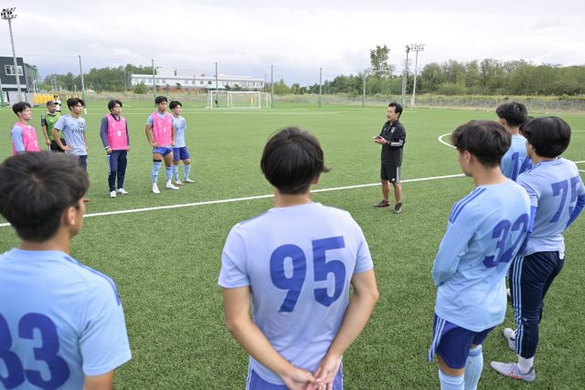 サッカーコートで学生に指導する新潟医療福祉大学男子サッカー部・佐熊裕和監督