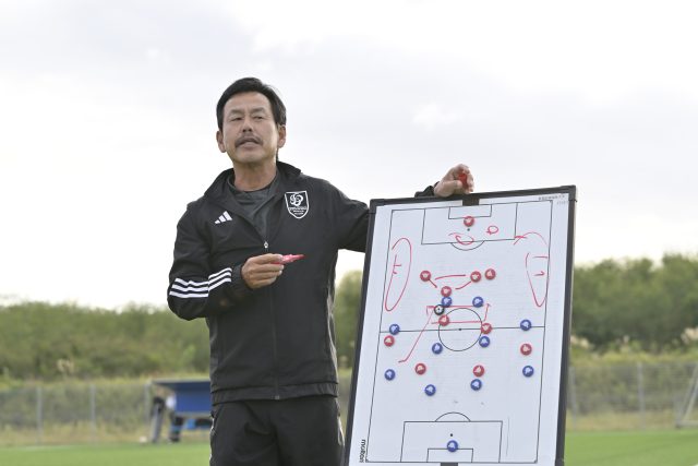 サッカーコートで学生に指導する新潟医療福祉大学男子サッカー部・佐熊裕和監督