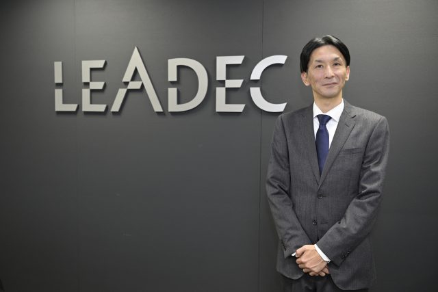 ロゴの前でほほえむリーデック株式会社 代表取締役 澤貴純氏