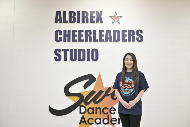 ロゴの前でほほ笑む株式会社アイ・シー・オースポーツマーケティングのスクールディレクター・五十嵐瑞穂氏