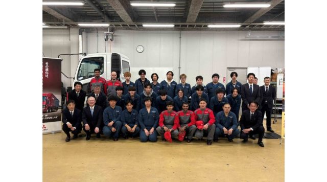 寄贈されたトラック車両を背景に記念写真を撮る専門学校 新潟国際自動車大学校の学生の様子